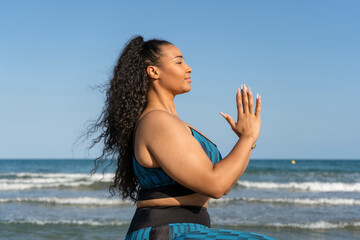 Fototapeta na wymiar Portrait young female relaxing practicing yoga with namaste on beach