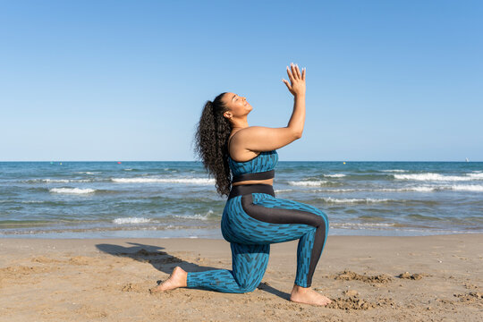 Woman practicing yoga exercises. Female relaxing with Namaste pose on beach