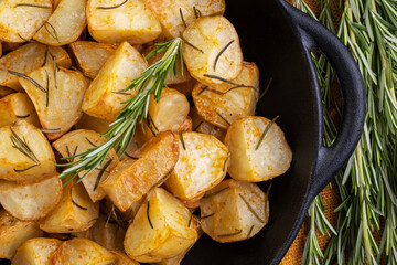 baked fried potatoes with rosemary, coarse salt, olive oil and spice paprika in iron skillet
