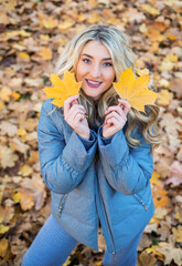 Trendy beauty. pretty girl has long curly blond hair. lady in fall padded jacket in autumn forest....
