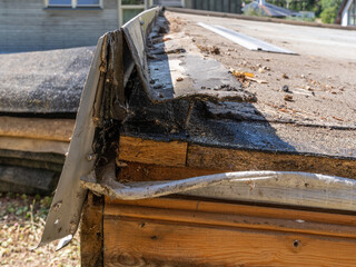 damaged flat roof edge, showing roof rafters, osb plate, waterproofing and metal profile edge.