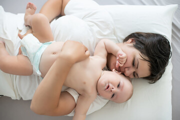 Fototapeta na wymiar Happy smiling mother and baby lying on bed at home