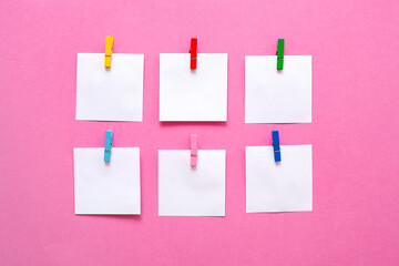 note paper and colorful clothespins on pink table