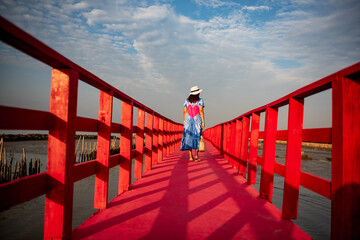 Young woman walking on the red boardwalk over the marshland.