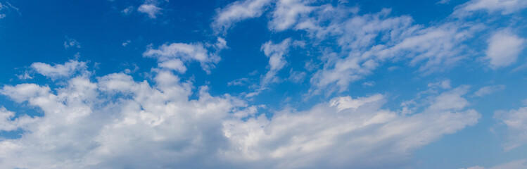 White clouds of different shapes on a blue sky, panorama