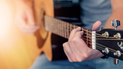 Fototapeta na wymiar Man playing acoustic guitar, guitar close up at shallow depth of field