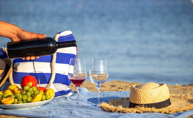 Pouring red wine into glasses, overlooking the sea, picnic by the sea. Selective focus