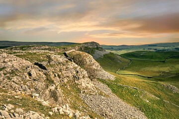Fototapeta na wymiar Soft pink light over the limestone features of Smearsett Scar near Stainforth in the Yorkshire Dales, shot in landscape