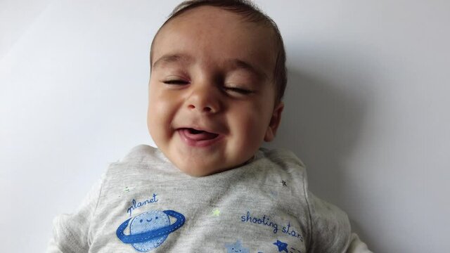 Baby smiling on a white background, Caucasian 4 months lying and smiling looking at camera