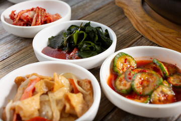 A view of several banchan dishes featuring oi muchim, kimchi, eomuk bokkeum, and miyeok muchim.