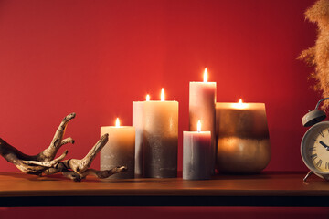 Burning candles and decor on table near color wall