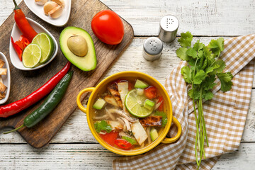 Composition with tasty Sopa de Lima soup on light wooden background