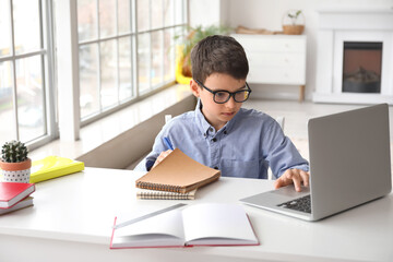 Fototapeta premium Little schoolboy studying online at home