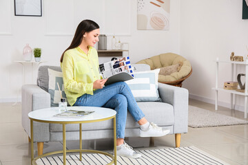 Young woman reading fashion magazine at home