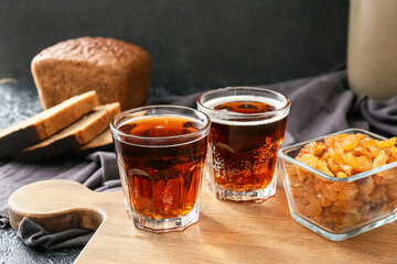 Glasses of fresh kvass and raisins on dark background