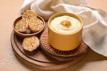 Bowl of tasty mashed potatoes with garlic on color wooden background