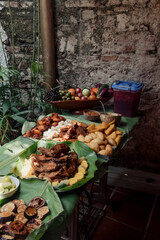 A spread of fried meat, fish and vegetables on banana leaf table