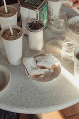 Beignets covered in powdered sugar on a table at a cafe