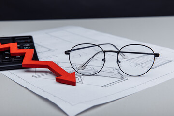 Financial and investment concept. Calculator, glasses and arrow down on architectural project