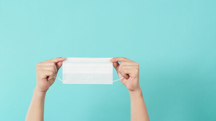 Two hand is holding surgical face mask .Medical mask on mint or Tiffany Blue background.