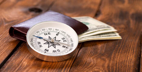 Compass and wallet with american dollars on wooden background as business concept