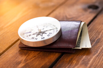 Compass and wallet with american dollars on wooden background as business concept