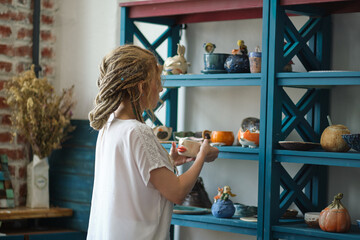 hostess of the ceramic workshop lays out her ceramic dishes on the shelves. feng shui concept....