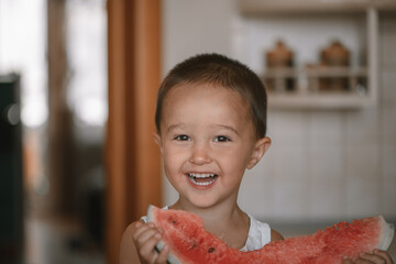 little boy 2-3 years old eating watermelon at home in the kitchen