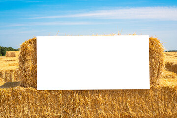 Harvest day mockup. White empty canvas on a sheaf of hay in a sunny summer day. Perfect template for agricultural or rural advertisements.