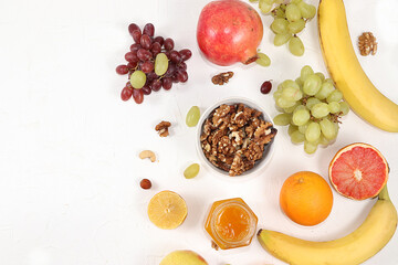 Healthy breakfast, food for children, yogurt with granola, oranges, banana and grapes on a light table. The concept of healthy and natural food, lifestyle.