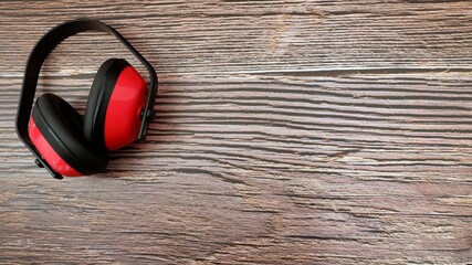 red ear protection lies as work protection on a wood background