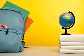 Blue backpack with school supplies with globe on books. Back to school concept