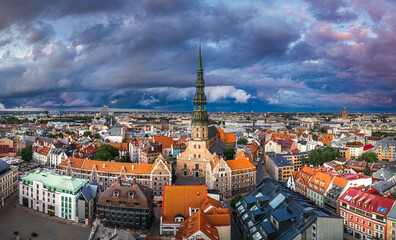 Obraz premium Incredible sunset over the Old town of Riga. Colorful sunlight shines over the rooftops of historic buildings and impressive church tower.