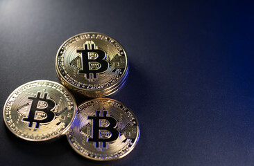 Piled up golden Bitcoin coins on dark background. Copyspace on right side