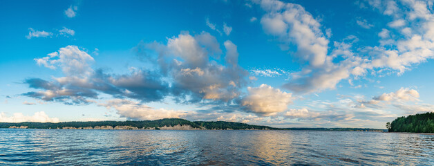 Panorama of calm lake, Kama river blue sky with clouds reflected in the water.
