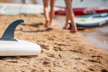 Background with paddle board, sup on a sand with people legs behind