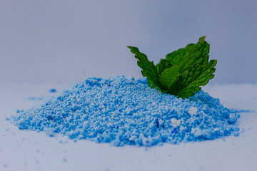 Eco-friendly washing powders. Ecological blue soap powder and green leaves.