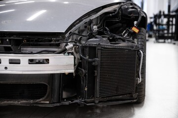 Damaged sports car with dismantled fender - visible suspension elements, oil and air coolers