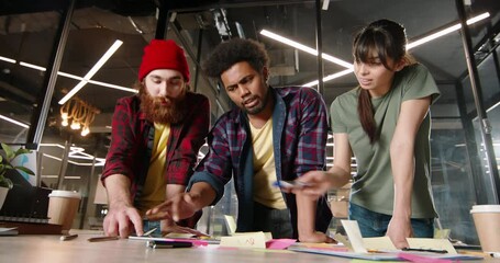 Millennial students discussing ideas for project. Creative diverse team brainstorming in office, making plans and strategies - teamwork, education low angle 4k footage