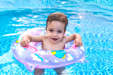 beautiful baby learning to swim in the pool with her float