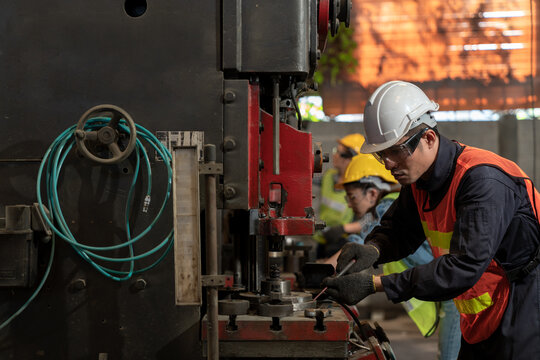 Technician engineer wearing hard hat and safety glasses maintenance the machine in the factory