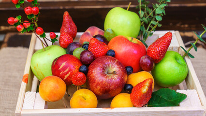 Summer fruit, berry assortment. Big apple, plum, apricot, grape and strawberry. Colorful berries in wooden crate on the table.