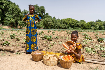 Two beautiful black sisters waiting at the roadside, selling fresh vegetables to people passing by