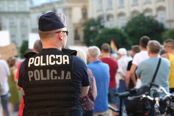 Polish policeman  officer in uniform watching protesting people in the street 