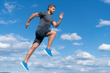 energetic man athlete with muscular body run in sportswear outdoor on sky background, motivation.