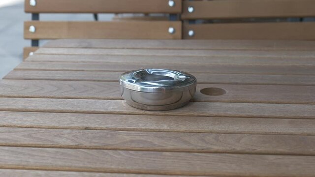 An ash tray on a table at a street cafe.