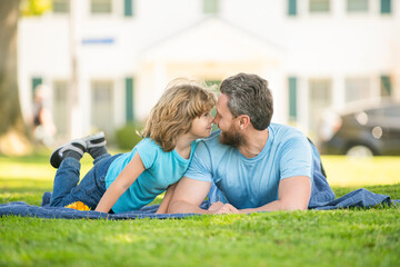 happy dad with son relax together on green park grass, fatherhood