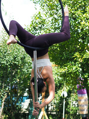 Attraktive junge Frau, die draußen im Garten Pole Dance trainiert und an den Gymnastikreife...