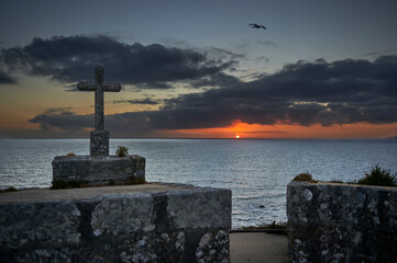 sunset from the ramparts with a seagull hovering around a stone cross
selective focus
