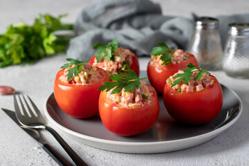 Tomatoes stuffed with ham and cheese on a gray plate on a light background